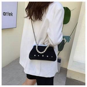 Detail of a black rhinestone crossbody bag with heart-shaped clasp and pearl handle