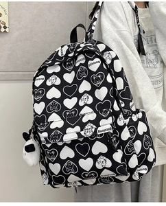 Detail of a nylon backpack with bear print, heart patterns, and a cute panda plush charm