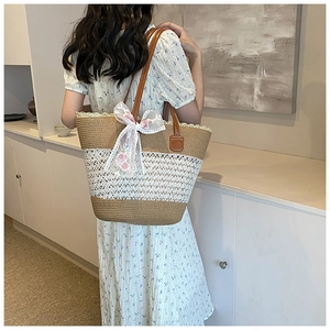 Detail of straw tote bag with lace mesh, pink flower embroidery, and a large bow