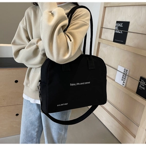 Detail of black fabric tote bag featuring Enjoy life and travel white text print