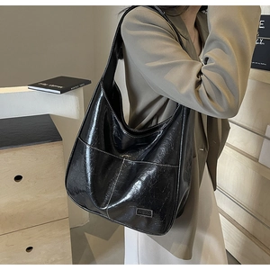 Close-up of black glossy PU leather hobo bag with pleated texture and fashion label