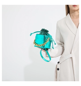 Dettaglio mini borsa a secchiello blu metallizzato con catena dorata e sacchetto verde
