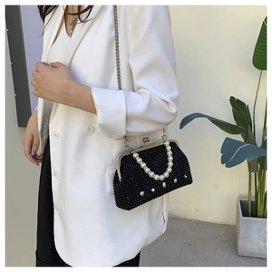 Chic black beaded evening bag with pearl handle and silver chain strap on a model
