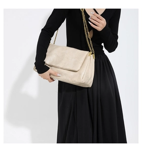 Detailed texture of the beige PU leather flap bag with gold chain strap on a model