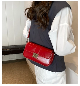 Close-up of a red patent leather baguette bag with silver buckle and thin strap