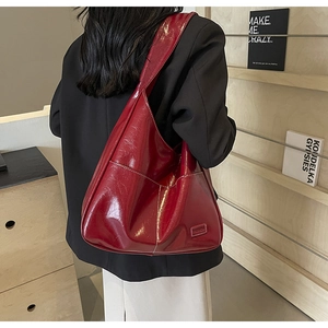 Detail of dark red PU shoulder bag with white contrast stitching and fashion label