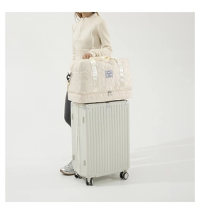 Detail of quilted beige fabric travel bag with star stitching and bottom zipper compartment