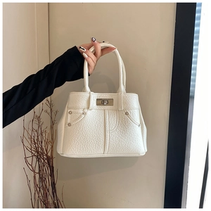 Detail der cremefarbenen PU-Tasche mit Lychee-Struktur, Metalldrehverschluss und Nieten