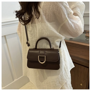 Detail view of dark brown PU leather crossbody bag with golden D-ring and top handle