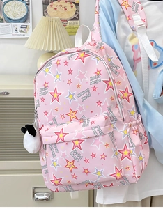Detailed view of a pink nylon backpack with multi-color star prints and cute plush charm