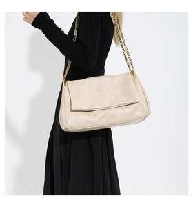 Detail of off-white PU leather shoulder bag with golden chain strap and pleated texture