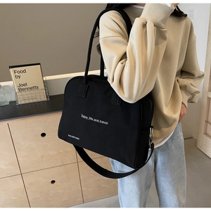 Detail of black fabric tote bag with Enjoy life and travel print and wide shoulder strap