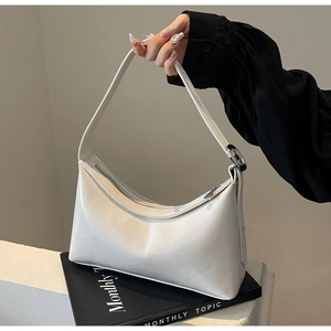 Detailed close-up of white croissant bag with glossy oil wax leather and silver hardware buckle