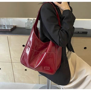 Detail shot of the glossy burgundy PU leather tote bag with a fashion label on front