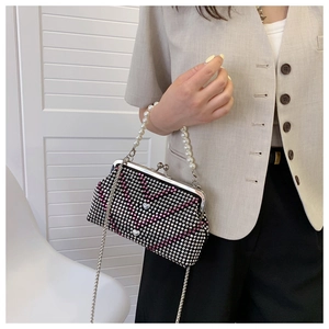 Detailed close-up of a sparkling rhinestone evening bag with heart patterns and pearl strap