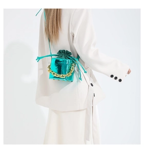 Mini borsa a tracolla verde metallizzato con catena dorata su blazer bianco