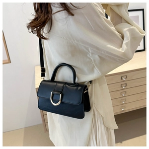 Minimalist black PU leather crossbody bag with gold D-buckle shown on a shoulder