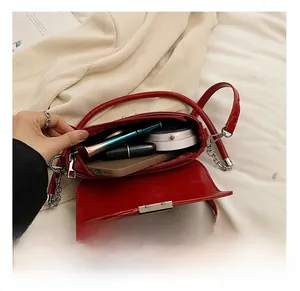 Top view of red PU leather shoulder bag showing inner capacity with cosmetics and phone