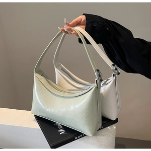 Detail of minimalist hobo shoulder bags in light green and cream white glossy PU leather
