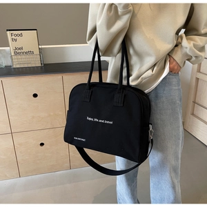 Detail of black canvas tote bag showing thick fabric texture and long shoulder strap