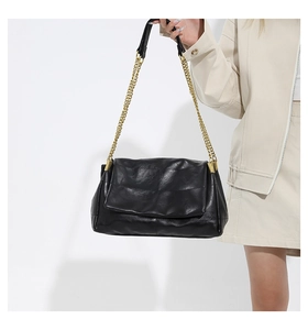 Detail of black quilted PU leather shoulder bag with gold chain strap and aged texture
