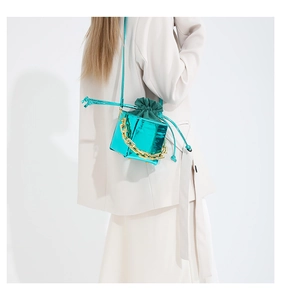 Dettaglio mini borsa a secchiello blu metallizzato con catena d'oro e velluto verde
