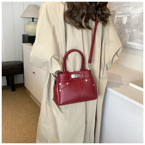 Detail der weinroten PU-Leder Umhängetasche mit Silberdrehverschluss am Model in Beige