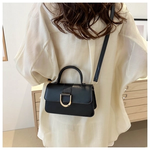 Detail of black matte PU leather bag with golden D-shaped buckle worn by model