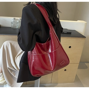 Close-up of stylish burgundy PU leather tote bag with glossy finish on a fashion model