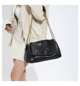 Close-up of black PU leather shoulder bag with double golden chain straps and texture detail