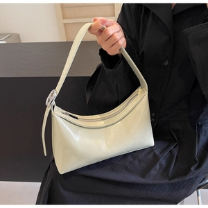 Detail of glossy beige PU leather baguette bag with silver zipper and metal hardware