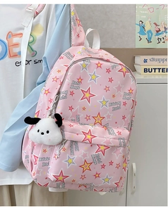 Close-up of pink nylon backpack with star patterns and a cute white puppy plush charm