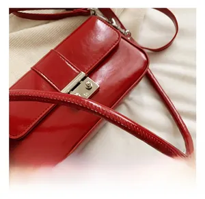 Detail of the bright red faux leather crossbody bag with a silver metal push lock closure