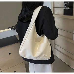 Detail view of cream white PU leather tote bag with wide strap and fashion logo patch