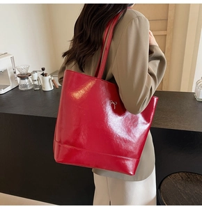 Detailed view of glossy red PU leather tote bag with elegant silver bow decoration