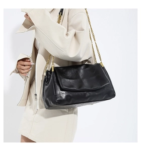 Detail of black faux leather handbag with large quilt pattern and gold chain strap