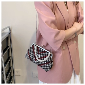 Close-up of sparkling rhinestone handbag with pearl handle and metal chain strap