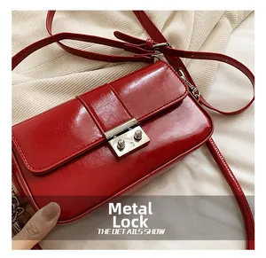 Detail of red glossy PU leather shoulder bag with sleek silver metal industrial lock