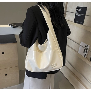 Close-up of white glossy PU leather shoulder bag with minimalist fashion logo detail