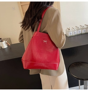 Minimalist bright red PU tote bag with silver bow detail shown on model in cafe