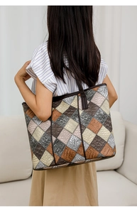 Detail of large PU leather tote bag with multi-texture patchwork design shown on shoulder