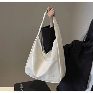 Detailed view of glossy white PU leather tote bag with a fashion tag and front pocket