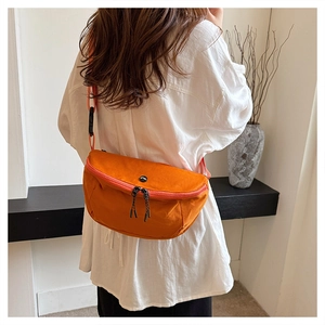 Detail view of vibrant orange nylon crossbody bag featuring double zippers and round logo