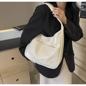 Detail of white glossy PU leather shoulder bag with FASHION label on black suit