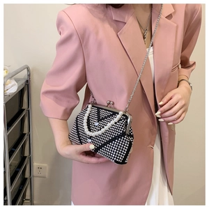 Detail of elegant black evening bag with heart rhinestone and faux pearl handle strap