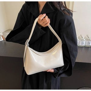 Detail of minimalist cream PU leather hobo bag with silver zipper and metallic charm