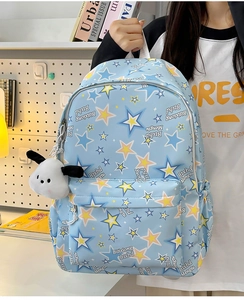 Detail of light blue nylon backpack with star pattern and cute plush dog pendant charm