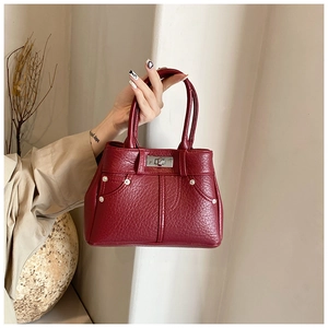 Detail der weinroten Handtasche aus PU-Leder mit silbernem Drehverschluss und Nieten