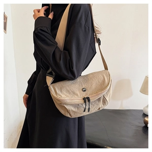 Detail of light beige washed nylon crossbody bag featuring textured fabric and wide strap