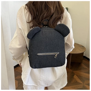 Detail view of denim backpack showing bear ear design and metal zipper pocket on the back